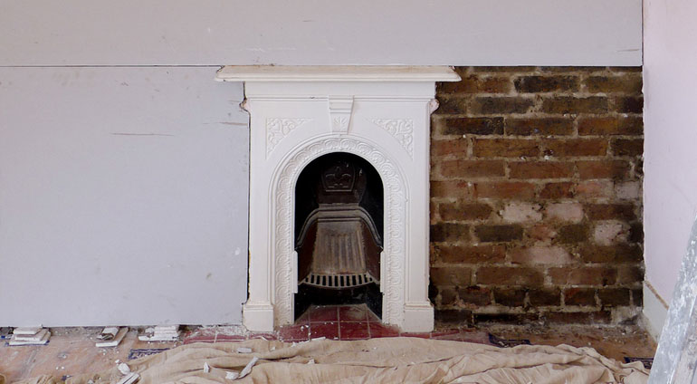 Partially boarded wall and fireplace